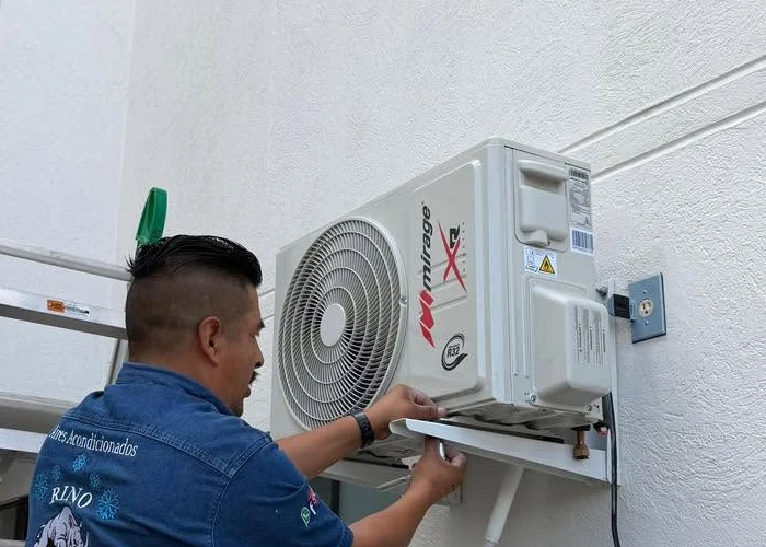 Técnico de Rino conectando una unidad exterior de aire acondicionado.